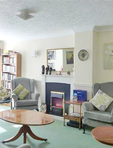 Communal lounge area with soft seating, coffee tables and a fireplace 