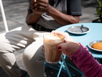 Close up of a resident's arm holding a coffee sitting outside