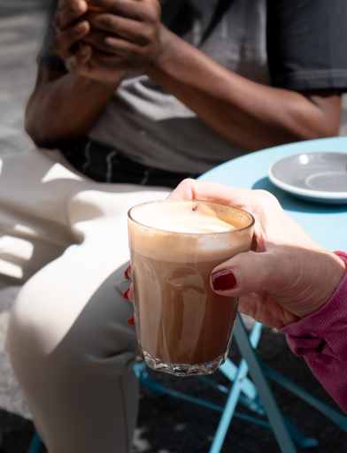 Close up of a resident's arm holding a coffee sitting outside 