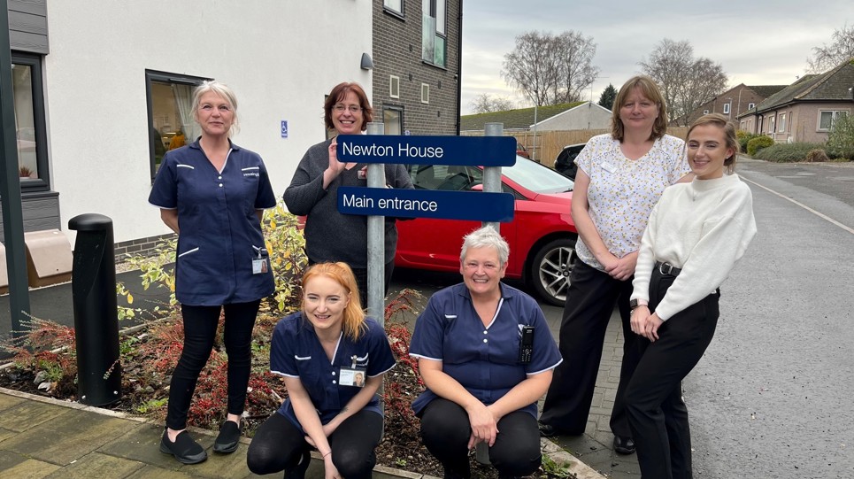 A group photo of colleagues carers and managers outside Newton House Extra Care scheme