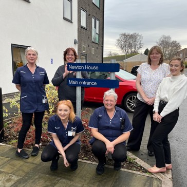 A group photo of colleagues carers and managers outside Newton House Extra Care scheme