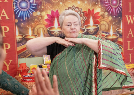 Woman celebrating Diwali while dressed in a green Sari