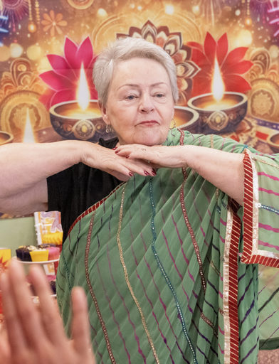 Woman celebrating Diwali while dressed in a green Sari 