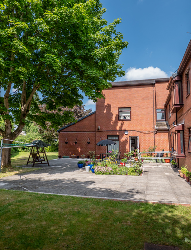 William Griffiths Court External gardens, a tree, flowerbeds, potted plants and seating 