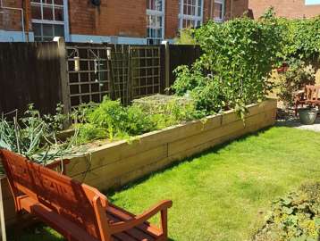 Communal garden area with large planter and bench at Amos Court