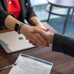 Two business professionals shake hands across a table