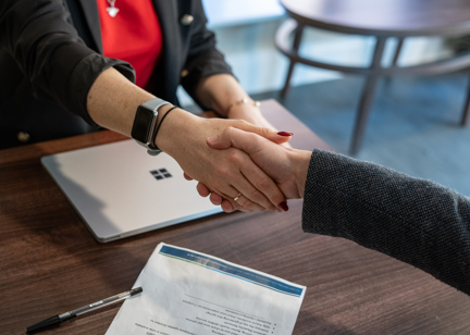 Two business professionals shake hands across a table
