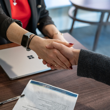 Two business professionals shake hands across a table