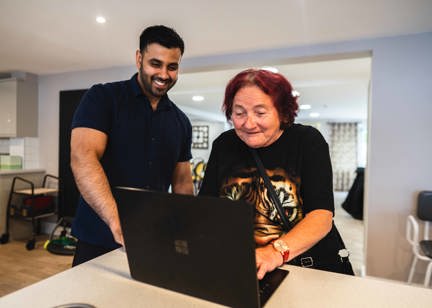 Resident and employee on a laptop computer in the communal lounge