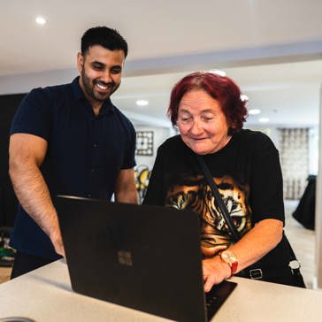 Resident and employee on a laptop computer in the communal lounge