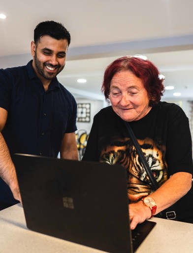Resident and employee on a laptop computer in the communal lounge 