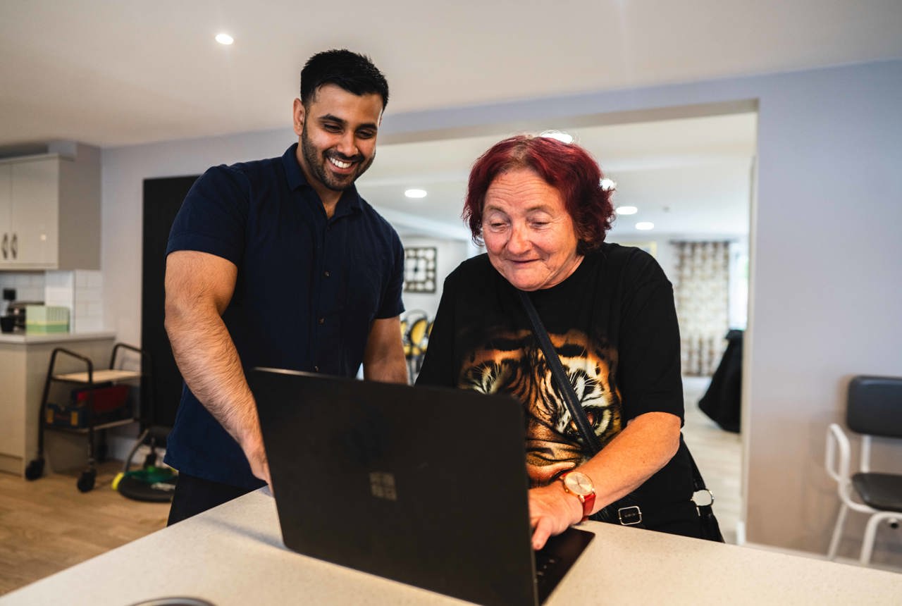 Resident and employee on a laptop computer in the communal lounge