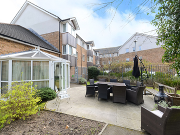 Patio area outside of the conservatory with large garden furniture set and parasol umbrella