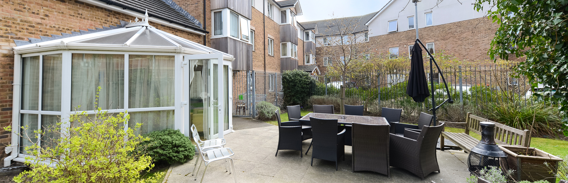 Patio area outside of the conservatory with large garden furniture set and parasol umbrella