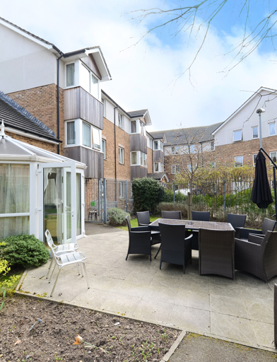 Patio area outside of the conservatory with large garden furniture set and parasol umbrella