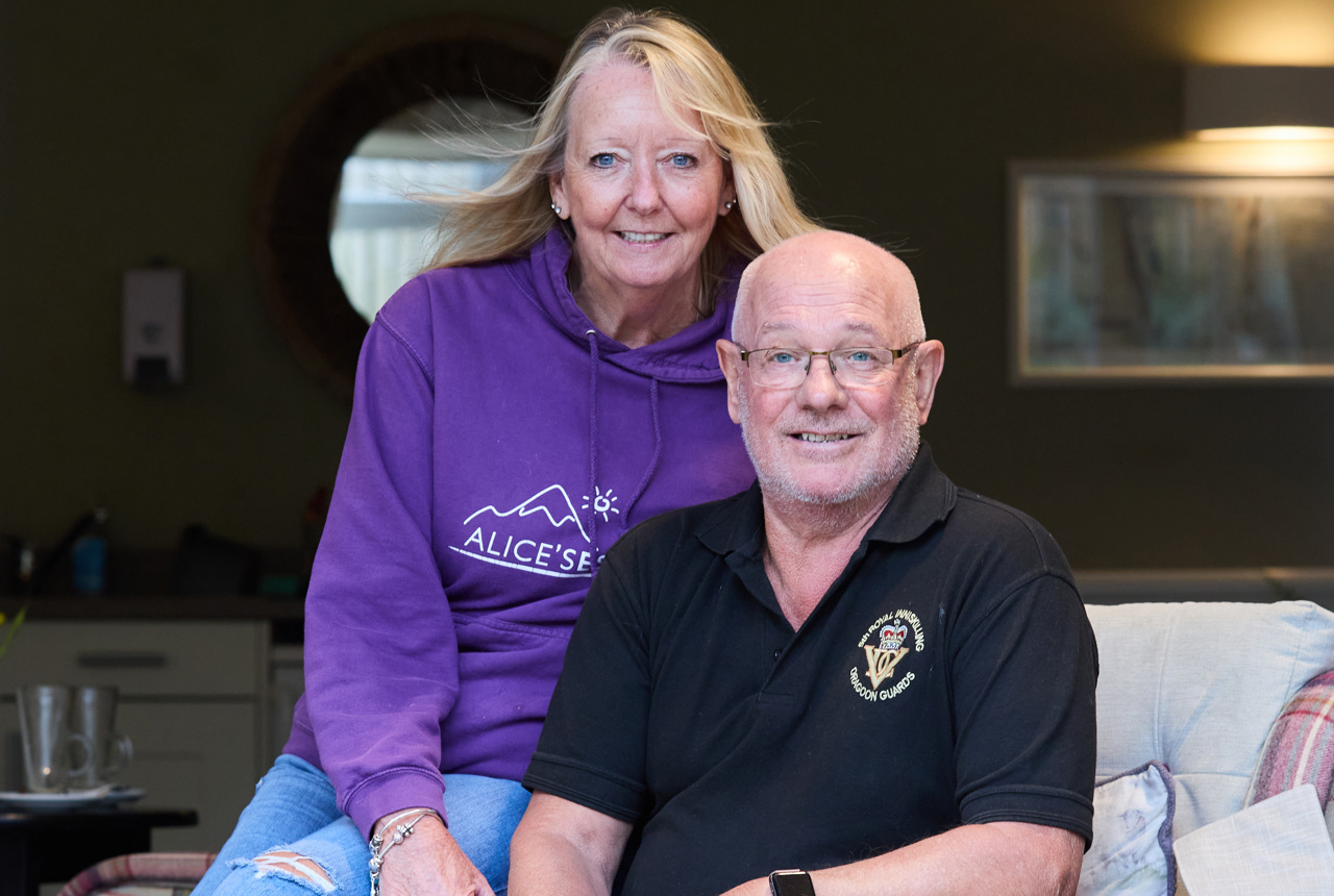 A couple who are residents smiling with their dog in the communal lounge