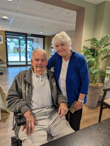 Residents Valerie and Peter smiling in a lobby area.