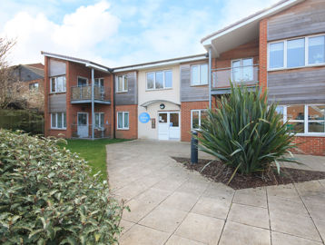 The main entrance of Alfred Deller Court with large grassed plant and slabbed area