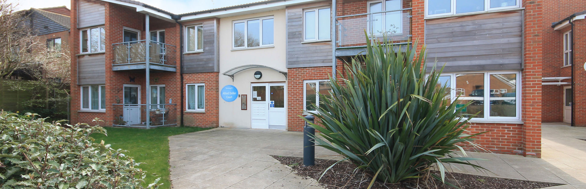 The main entrance of Alfred Deller Court with large grassed plant and slabbed area