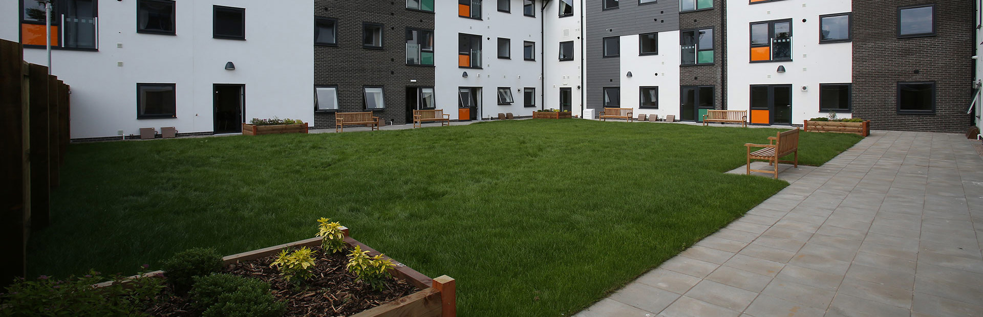 Large garden area with planters and benches around a grassed area