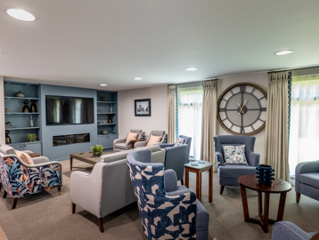 William Griffiths Court internal shot: Television area with a selection of seating chairs and sofas, decorated with a large clock and potted plants
