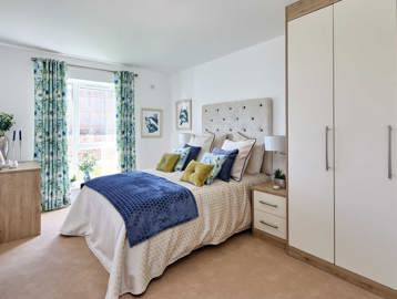 A bedroom furnished with a bed, wardrobe, side table and chest of drawers with a full length window to the rear