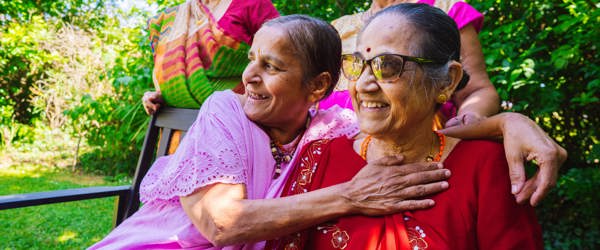 Four residents sitting in a garden smiling 