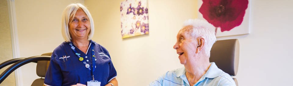 An Extra Care resident using gym equipment with help from a carer from Housing 21 