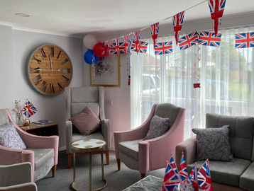 Residents' lounge with soft seating and coffee tables decorated with Union Jack bunting