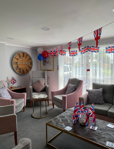Residents' lounge with soft seating and coffee tables decorated with Union Jack bunting 