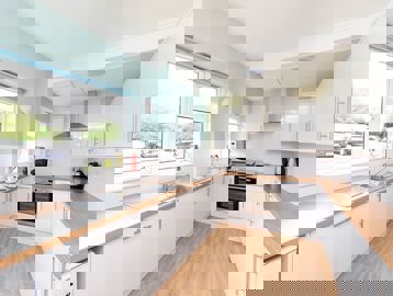 Large and bright communal kitchen with wooden flooring, sink, oven and extractor fan