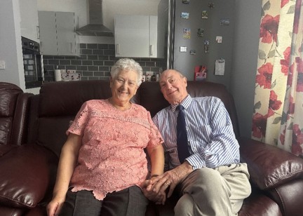 Vinnicombe Court residents David and Shirley sitting together on a sofa holding hands.