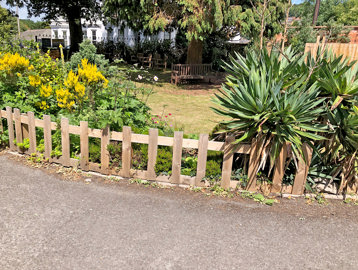 Short picket fence along the front of the communal garden with plants and flowers