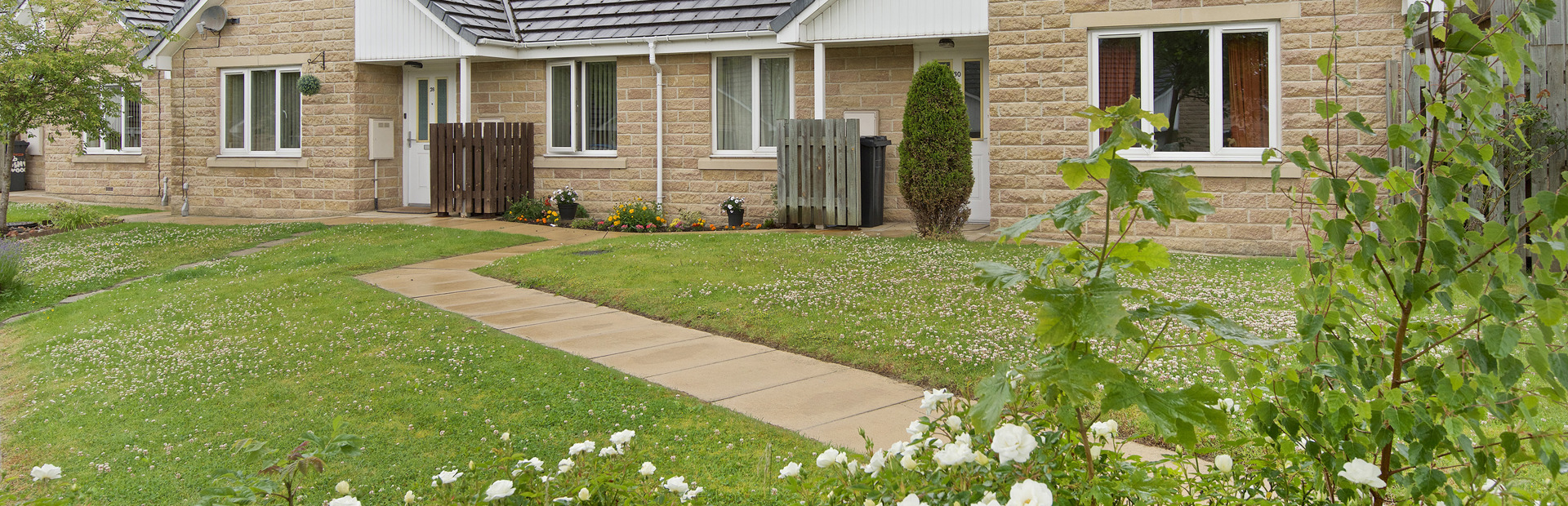 Flowers and green gardens to the front of bungalows