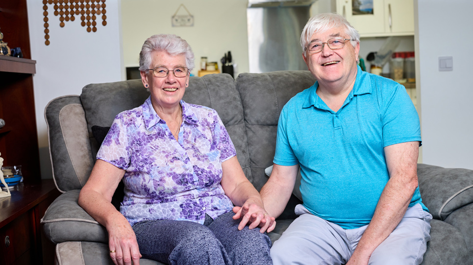 A couple holding hands while sat in their modern, bright living room