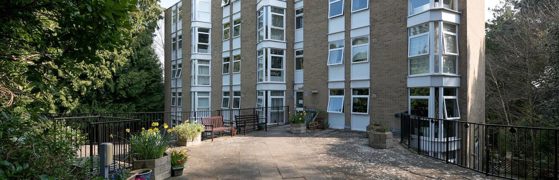 Large patio area with plants, flowers, trees and seating in the communal area
