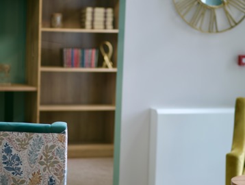 A close-up of a bookshelf and wall clock at Penfold Court in London