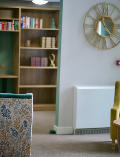 A close-up of a bookshelf and wall clock at Penfold Court in London 