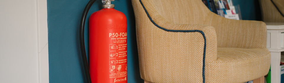 a fire extinguisher on a wall next to a chair 