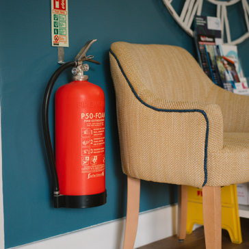a fire extinguisher on a wall next to a chair