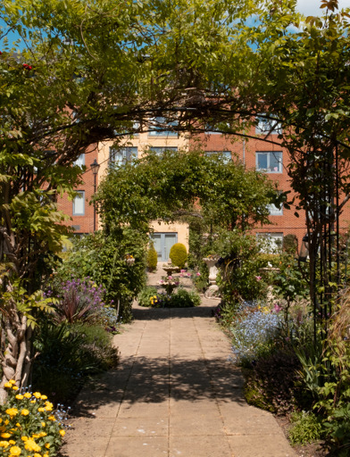 View through a series of archways in the garden covered in climbing plants 