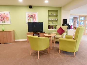 Communal lounge with comfy green seats and large TV screen