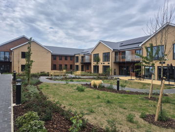 Landscape image showing the building of Extra Care scheme Michaelmas Court, with grass and tree's in front of the building
