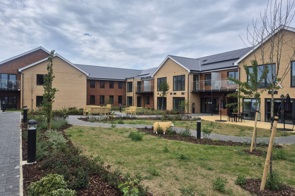 Landscape image showing the building of Extra Care scheme Michaelmas Court, with grass and tree's in front of the building