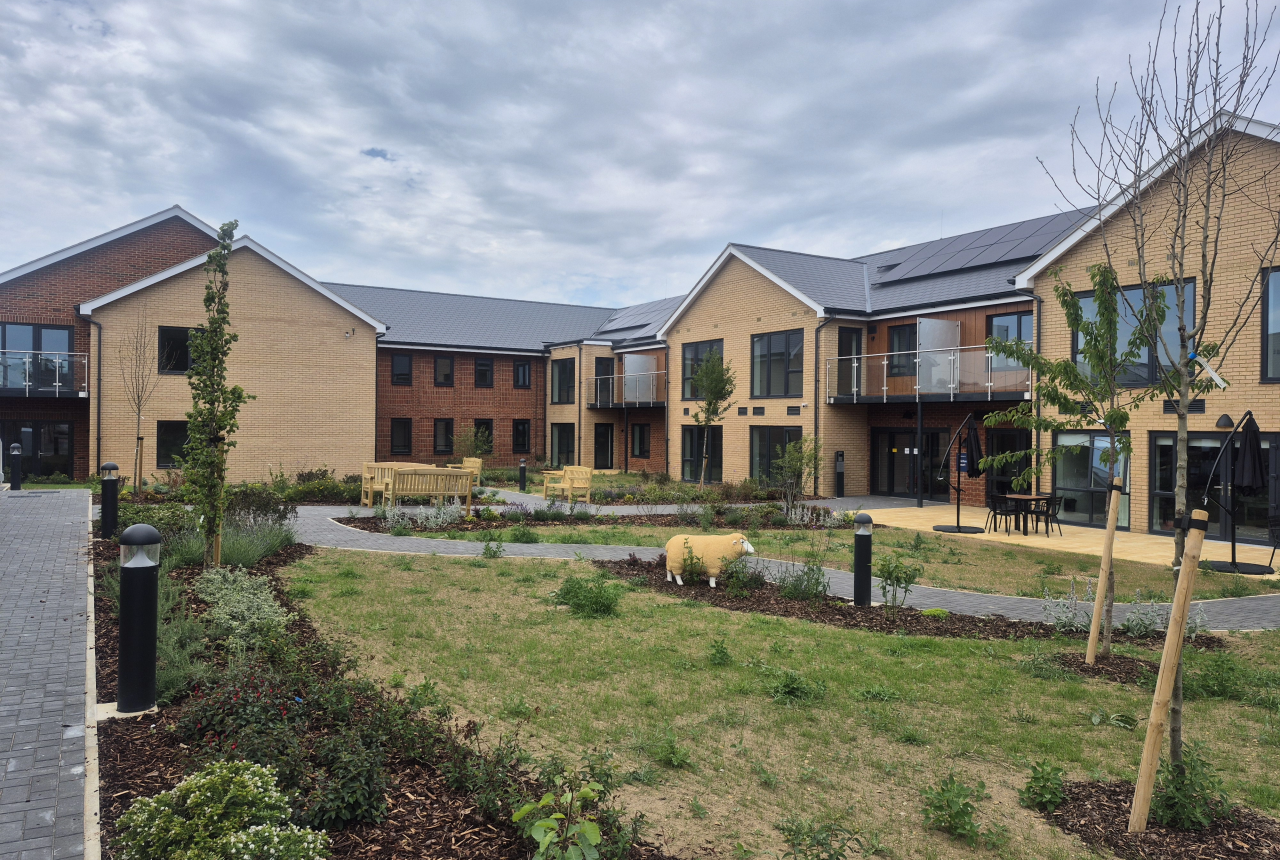 Landscape image showing the building of Extra Care scheme Michaelmas Court, with grass and tree's in front of the building