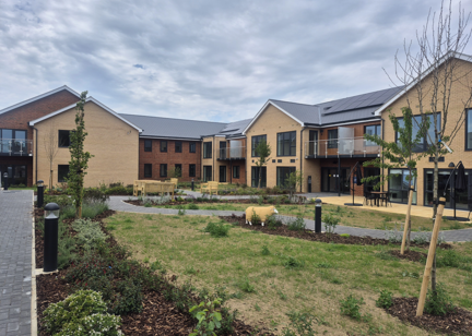 Landscape image showing the building of Extra Care scheme Michaelmas Court, with grass and tree's in front of the building