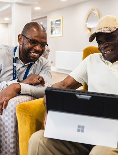 Resident and employee sitting down using a laptop 