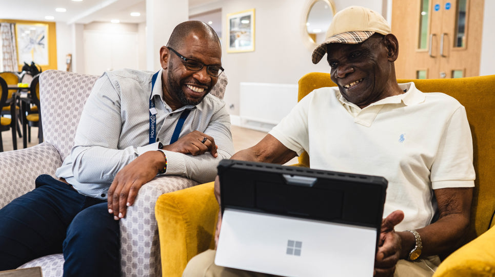 Resident and employee sitting down using a laptop