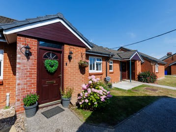 A row of bungalows with flowers and hanging baskets around the front door