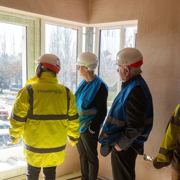 Four men in hard hats are looking at a new building